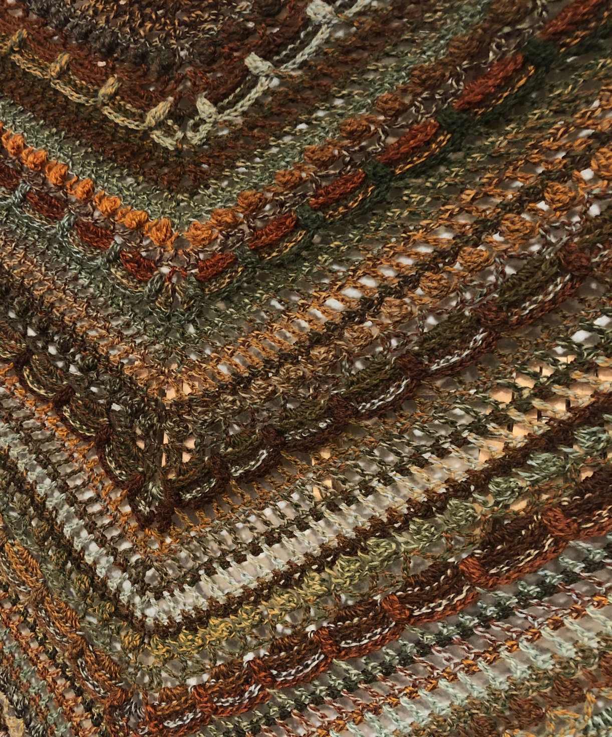 close-up view of crocheted shawl in browns and fall colors